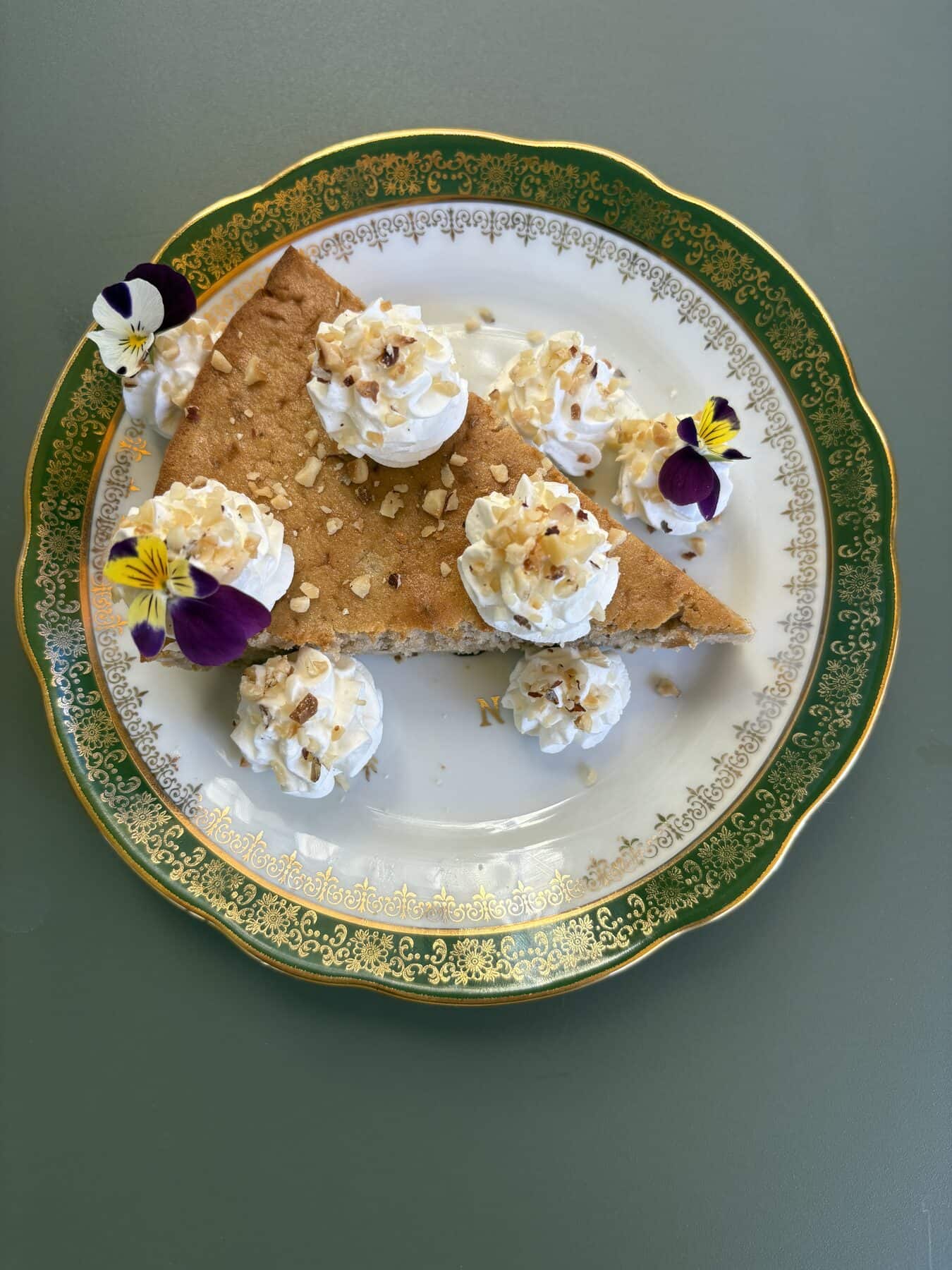 Moelleux à la châtaigne et aux noix, chantilly maison, sur une assiette verte à liseré doré.