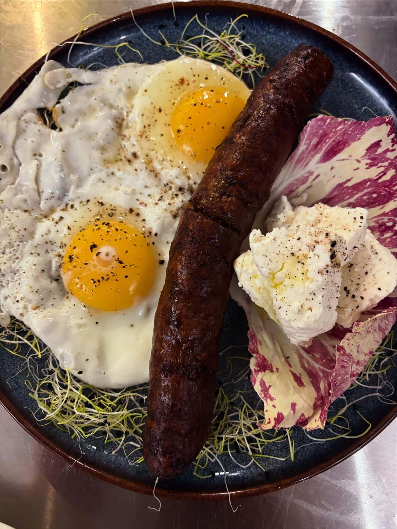 Figatelli grillé, œuf de ferme et brocciu dans une assiette de service.