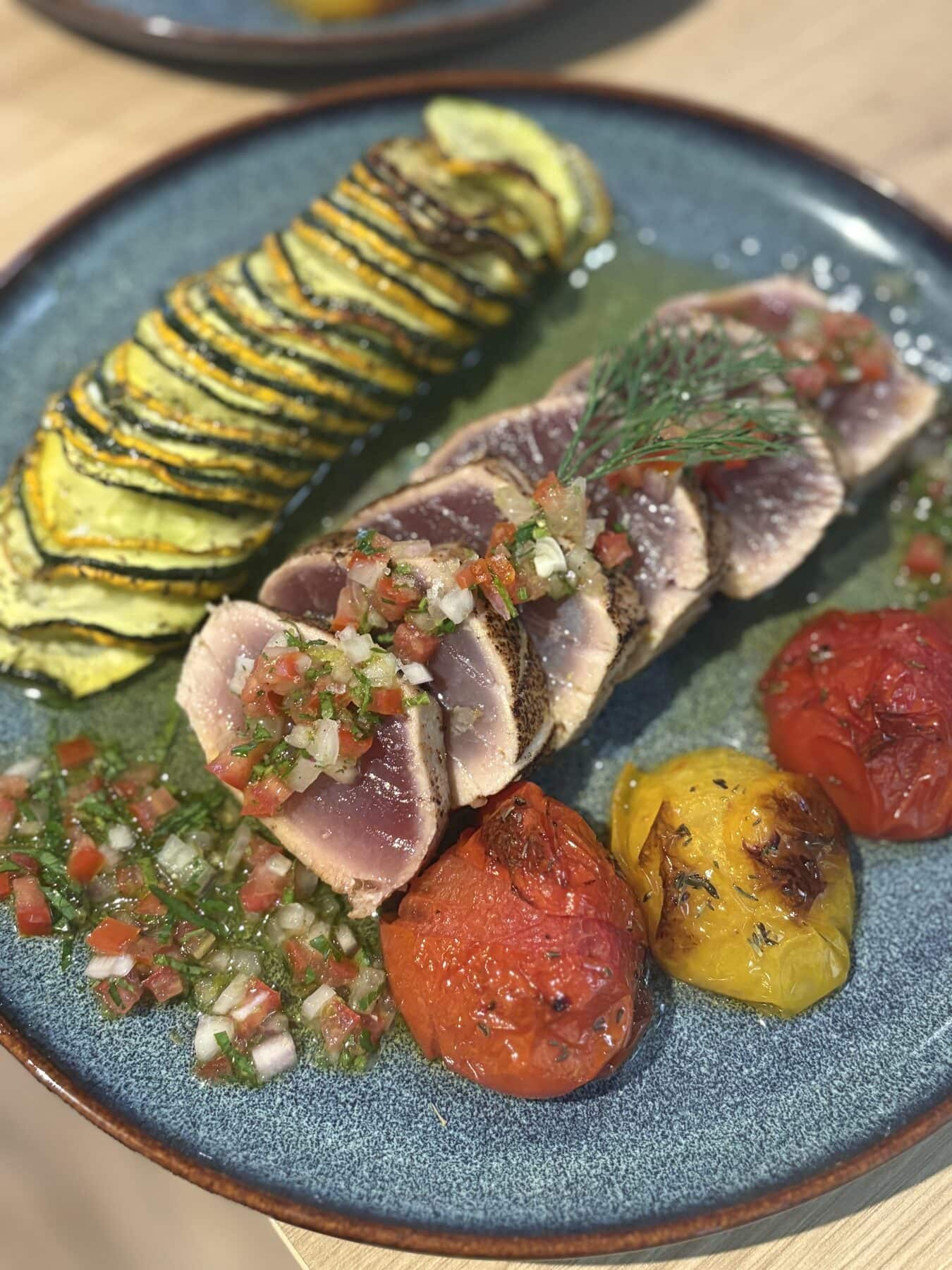 Mi-cuit de thon à la flamme, tian de courgette et tomates confites, assiette bleue.