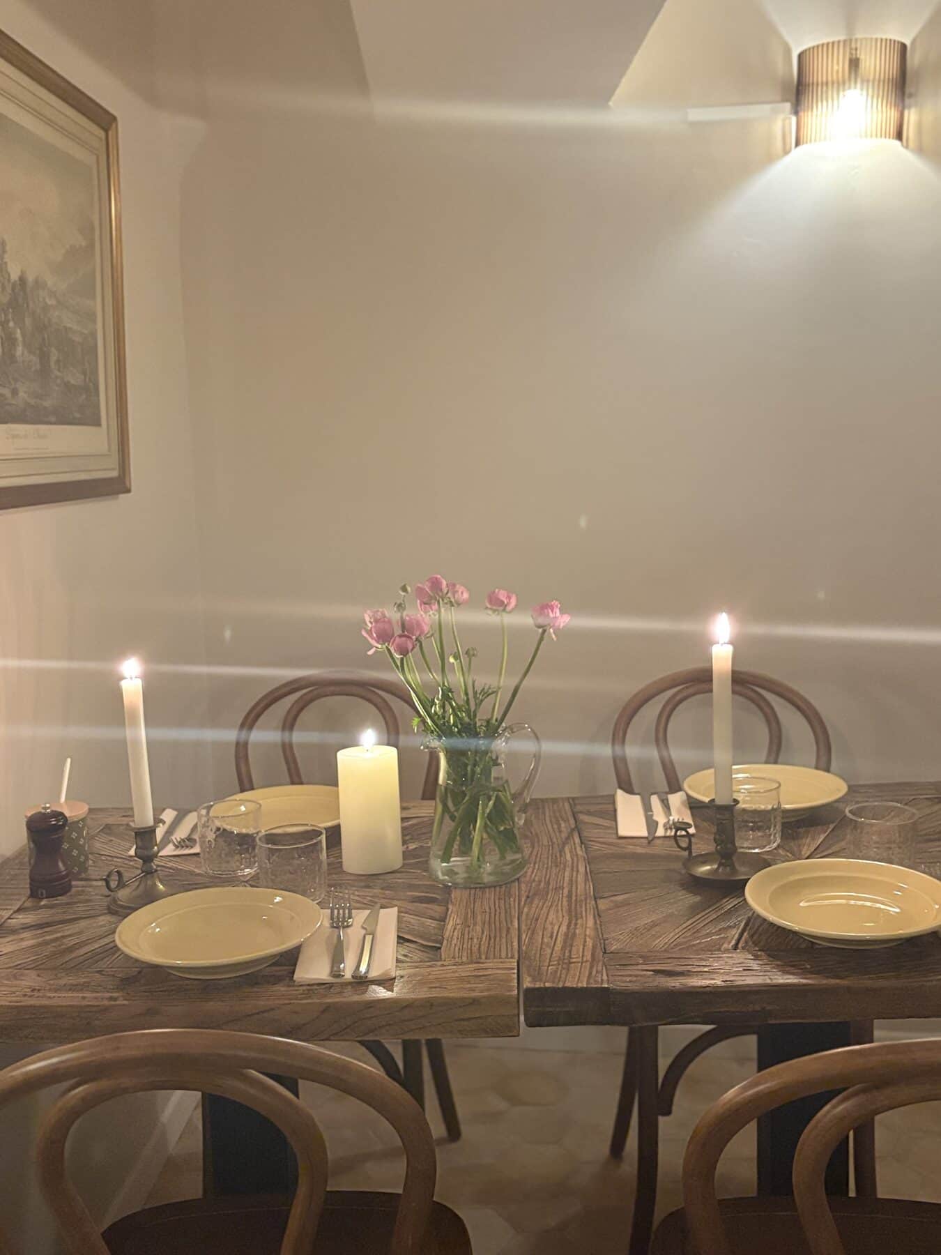 Table du soir éclairée à la bougie, verres et fleurs fraîches.