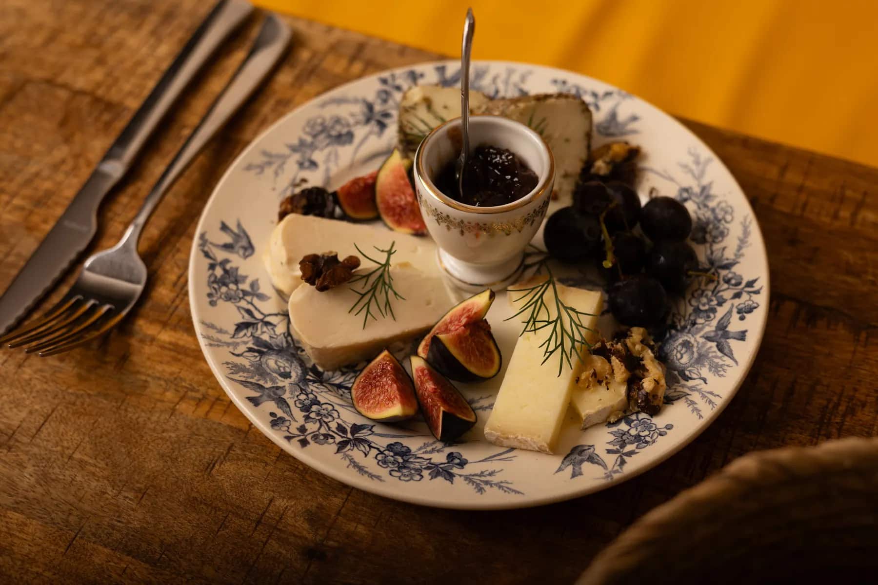 L’assiette de fromages servie sur la table en bois, couverts dressés.