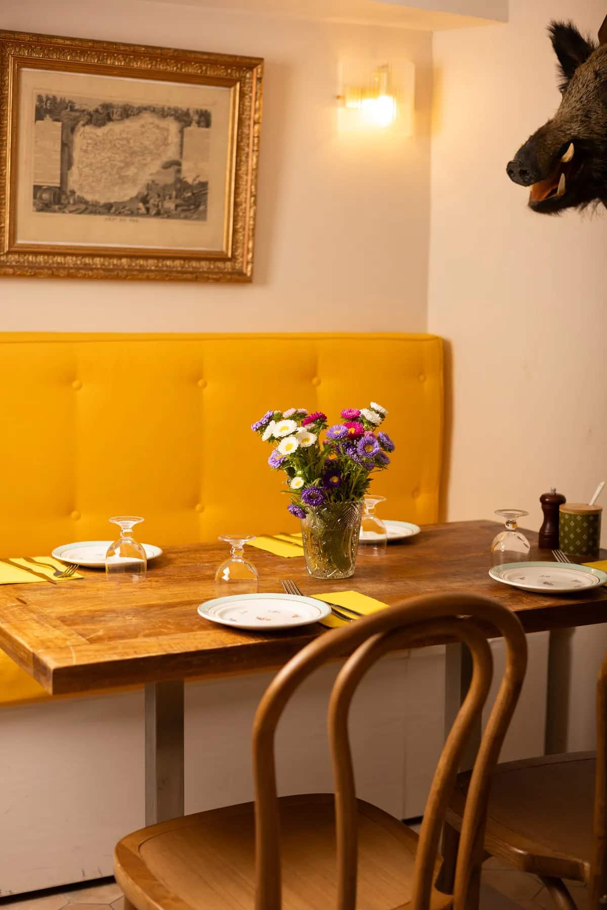 Une table dressée devant la banquette jaune, bouquet de fleurs fraîches.